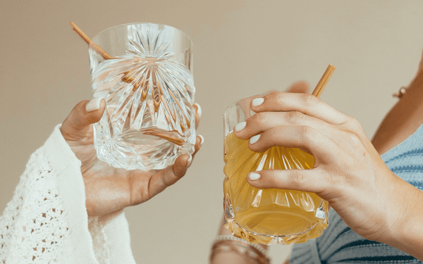 Two women holding cocktail glasses with eco-friendly HAY! Straws. Compostable drinking straws made from natural wheat stems. 