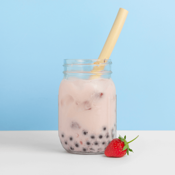 HAY! Straws Boba straw made from reed plant stems in a milk tea with a blue background and a strawberry garnish 